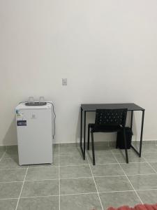 a table and a small refrigerator and a table and chair at Suítes JK in Paragominas