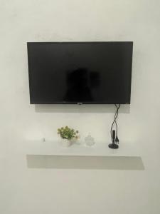 a flat screen tv hanging on a wall with a shelf at Suítes JK in Paragominas +5 photos
