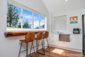 a kitchen with a counter with stools and a window at The Hideaway in Emu Park +9 photos