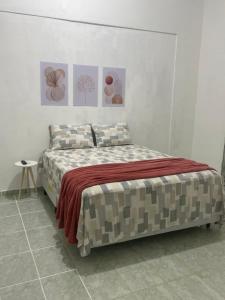 a bed in a white room with paintings on the wall at Suítes JK in Paragominas