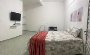 a bedroom with a bed and a flat screen tv at Suítes JK in Paragominas