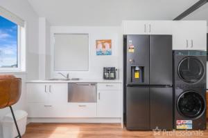 a kitchen with a refrigerator and a washer and dryer at The Hideaway in Emu Park
