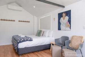 a bedroom with a bed and two chairs and a painting at The Hideaway in Emu Park