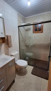 a bathroom with a shower and a toilet and a sink at Casa com piscina aquecida, 3 quartos e 3 camas extras in Capão da Canoa