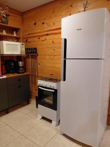 a white refrigerator in a kitchen with a stove at Casa com piscina aquecida, 3 quartos e 3 camas extras in Capão da Canoa