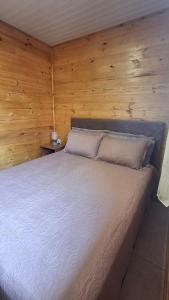 a bedroom with a bed in a wooden wall at Casa com piscina aquecida, 3 quartos e 3 camas extras in Capão da Canoa