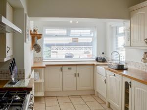 a kitchen with white cabinets and a large window at Wheelhouse 21 in Amble