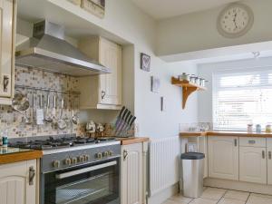 a kitchen with a stove and a sink and a clock at Wheelhouse 21 in Amble