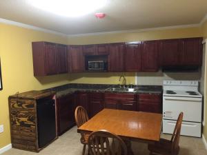 a kitchen with wooden cabinets and a wooden table and a table and a sink at Dragon INN & Suites in Fayette +33 photos
