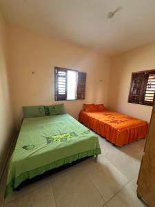 two beds in a room with orange sheets at Casa Amarela no Fortim in Fortim