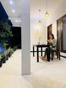 a woman sitting at a table in a room at Sea Breeze Heaven in Tangalle
