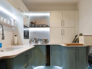 a kitchen with white cabinets and a sink at Mac Shack Cottage - Uk32376 in Ashen