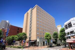 a tall building on a city street with buildings at Richmond Hotel Yokohama-Bashamichi in Yokohama