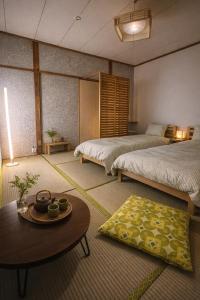 a room with two beds and a coffee table and a room with two beds at MACARA Guesthouse in Nichinan