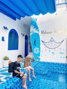 two boys sitting in a swimming pool with a surfboard at Robinson Homestay - Cù Lao Mái Nhà in Tuy An