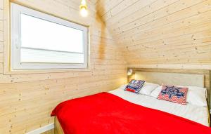 a red bed in a wooden room with a window at Stunning Home In Sarbinowo in Sarbinowo