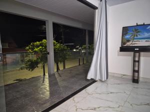 a room with a television and a balcony with plants at Quarto casal Nereidas bwc compartilhado in Guaratuba