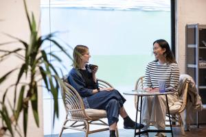 two women sitting at a table in chairs talking at MEANDER Taipei in Taipei