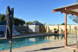 a swimming pool with an umbrella and a gazebo at Lancelin Lodge in Lancelin