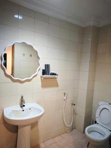 a bathroom with a sink and a toilet and a mirror at Pasadena Home in Tawau
