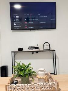 a tv on a wall above a table with a plant at Luxury Guest Home - 10 Min to JFK in Jamaica
