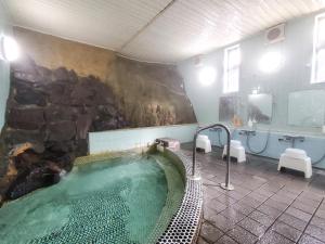a bathroom with a hot tub with a stone wall at 偕楽園 in Shirasaka