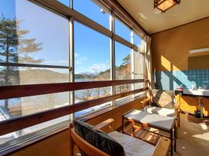 a room with large windows and a table and chairs at 偕楽園 in Shirasaka