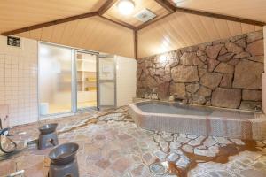 a large bathroom with a tub and a stone wall at Address Nozawa in Nozawa Onsen