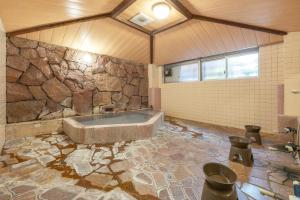 a bathroom with a tub in a stone wall at Address Nozawa in Nozawa Onsen