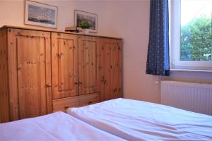 a bedroom with a wooden cabinet and a bed at Lütt Eddy in Kaltenhof