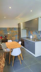 a kitchen with a wooden table and white chairs at Emma modern suite in Kourou