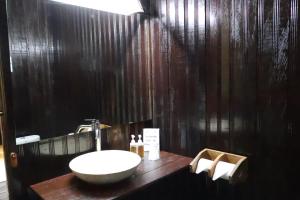 a bathroom with a sink and a black wall at Rimba Orangutan Ecolodge in Kampungcina +39 photos