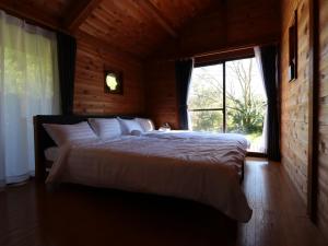 a bedroom with a large bed with a large window at La villetta 白浜 in Minamiboso