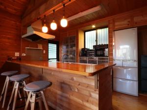 a kitchen with a wooden counter and stools at a bar at La villetta 白浜 in Minamiboso