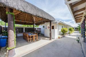 a patio with a table and a straw roof at Badi's Place in Moalboal