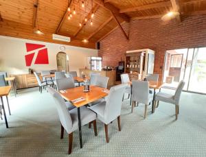 a dining room with wooden tables and white chairs at Federation Motel Resort - Corowa in Corowa