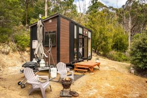 a tiny house with two chairs and a table at Wattle Grove Hideaway by Tiny Away in Wattle Grove