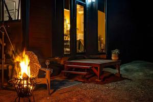a campfire with a table and a bench next to a house at Wattle Grove Hideaway by Tiny Away in Wattle Grove