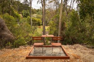 a bench sitting on the ground in the woods at Wattle Grove Hideaway by Tiny Away in Wattle Grove