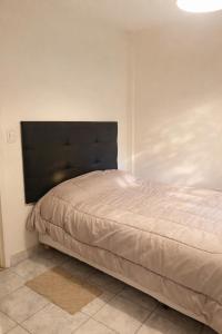 a bed in a bedroom with a black headboard at Dpto SAN MARTIN in Azul