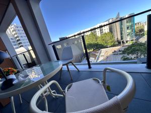 a balcony with a glass table and chairs and a window at Connect 204 in Auckland
