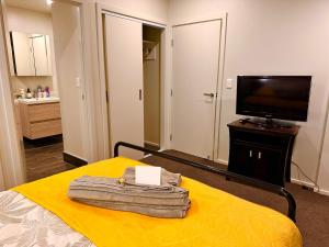 a bedroom with a yellow bed with a television at Connect 204 in Auckland