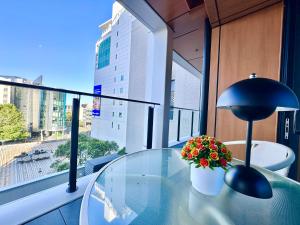 a glass table with a lamp and flowers on a window at Connect 204 in Auckland