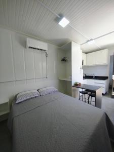 a bedroom with a bed and a kitchen with a table at Loft Navegantes Próximo Aeroporto e BR 101 in Navegantes