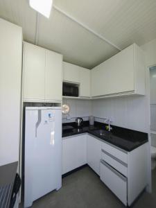 a kitchen with white cabinets and a refrigerator at Loft Navegantes Próximo Aeroporto e BR 101 in Navegantes