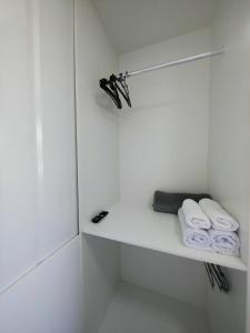 a white bathroom with white towels on a shelf at Loft Navegantes Próximo Aeroporto e BR 101 in Navegantes