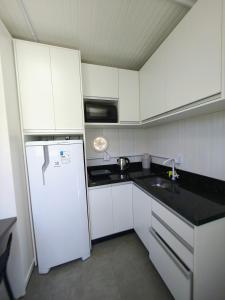 a kitchen with white cabinets and a white refrigerator at Loft Navegantes Próximo Aeroporto e BR 101 in Navegantes +6 photos
