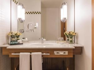 a bathroom with a sink and a mirror and flowers at Sofitel Grand Sopot in Sopot