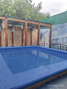 a blue swimming pool with a wooden pergola at Hotel y Hostal AH MUN in Mérida