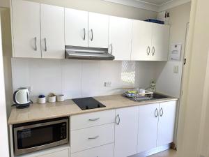 a kitchen with white cabinets and a microwave at Bulgon Lodge in Collinsville